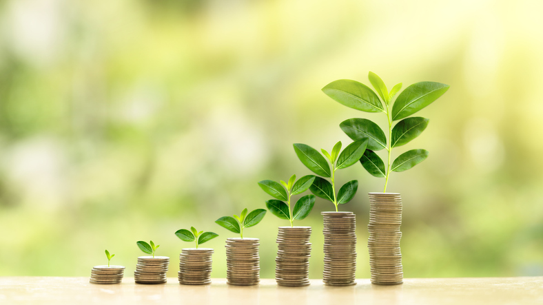 Sustainable finance represented by stacks of coins with plants growing from them