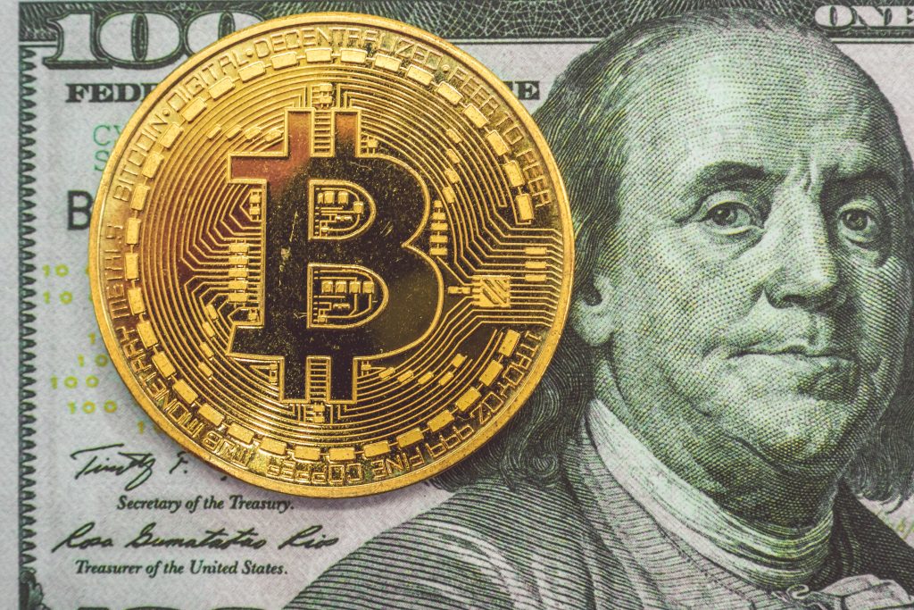 Bitcoin coin on top of 100 dollar bill 